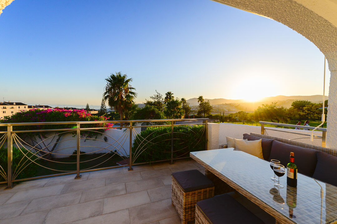 Du vin et un coucher de soleil dans le coin salon de la terrasse
